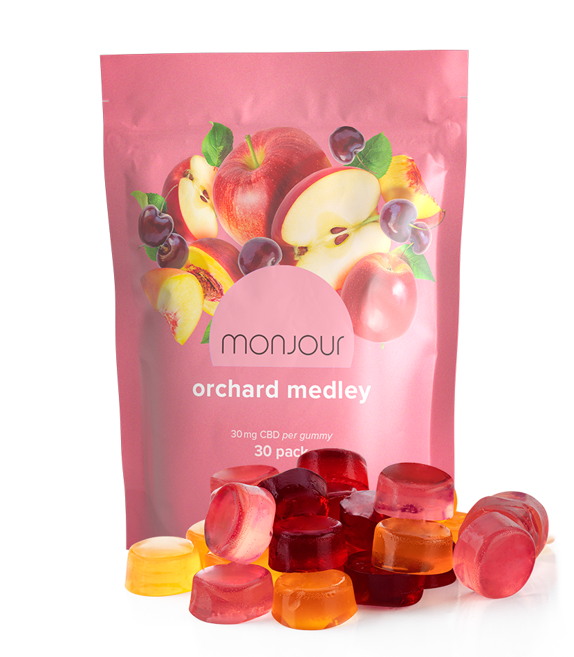 A peach pouch of Orchard Medley with a pile of gummies.
